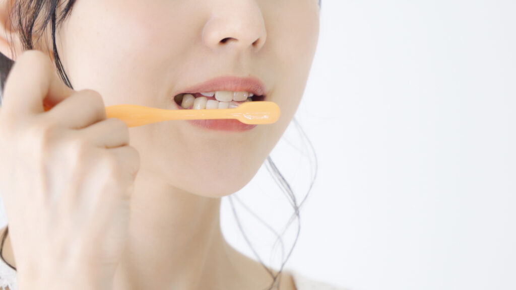 インプラントがぐらつくのを予防するために丁寧に歯磨きをする女性