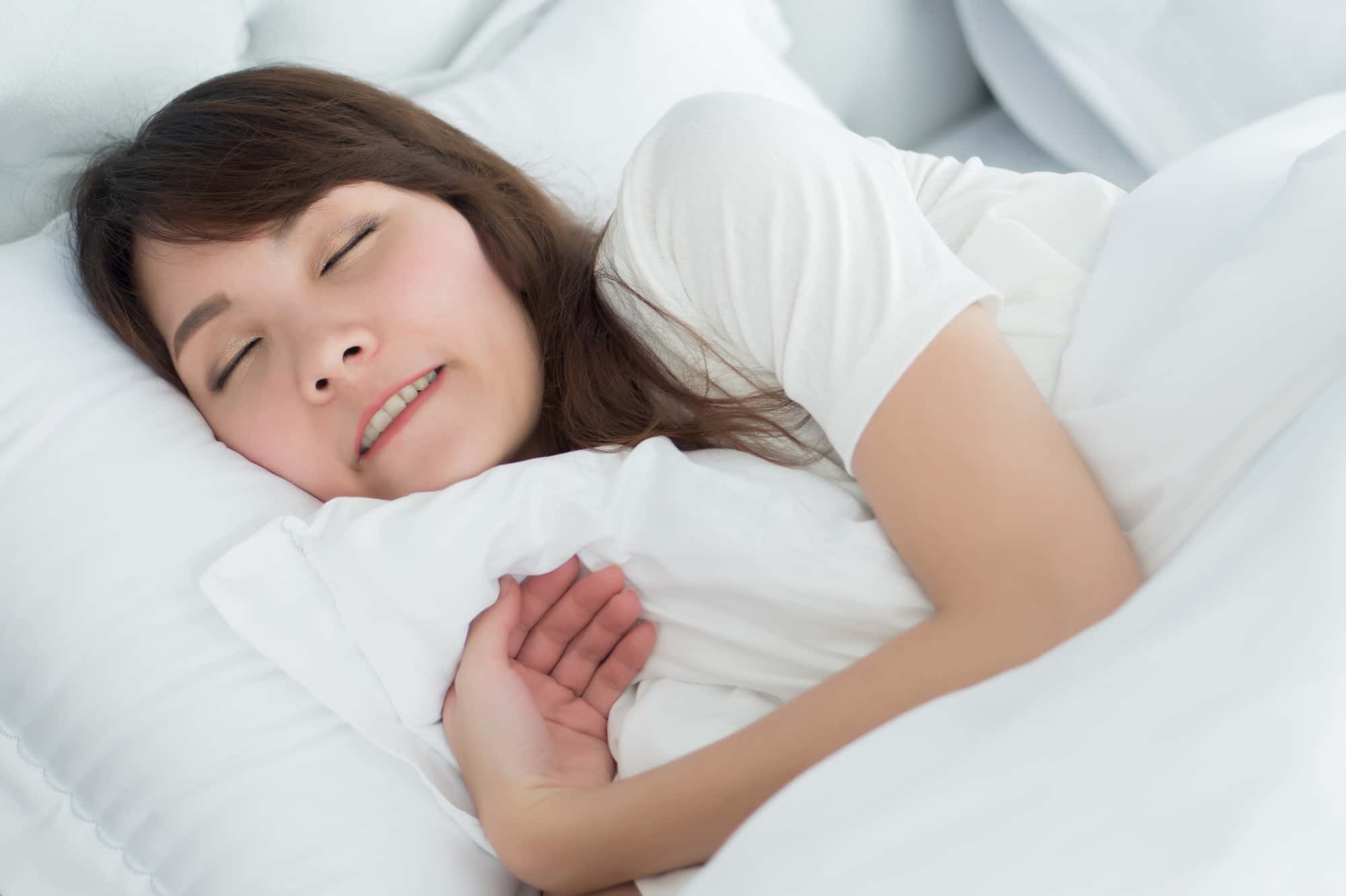 顎関節症の原因になる歯ぎしりをしながら眠る女性