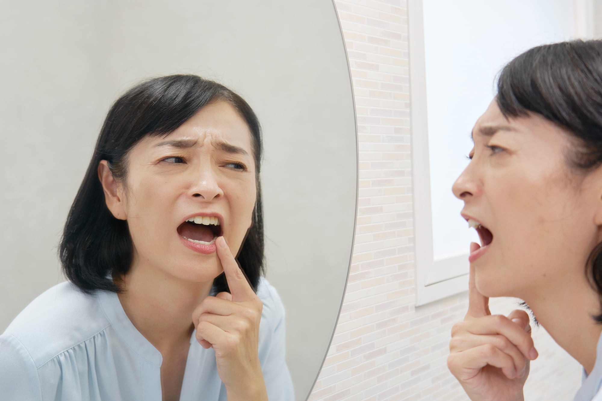 インプラント治療後に痛みを感じて鏡を見る女性