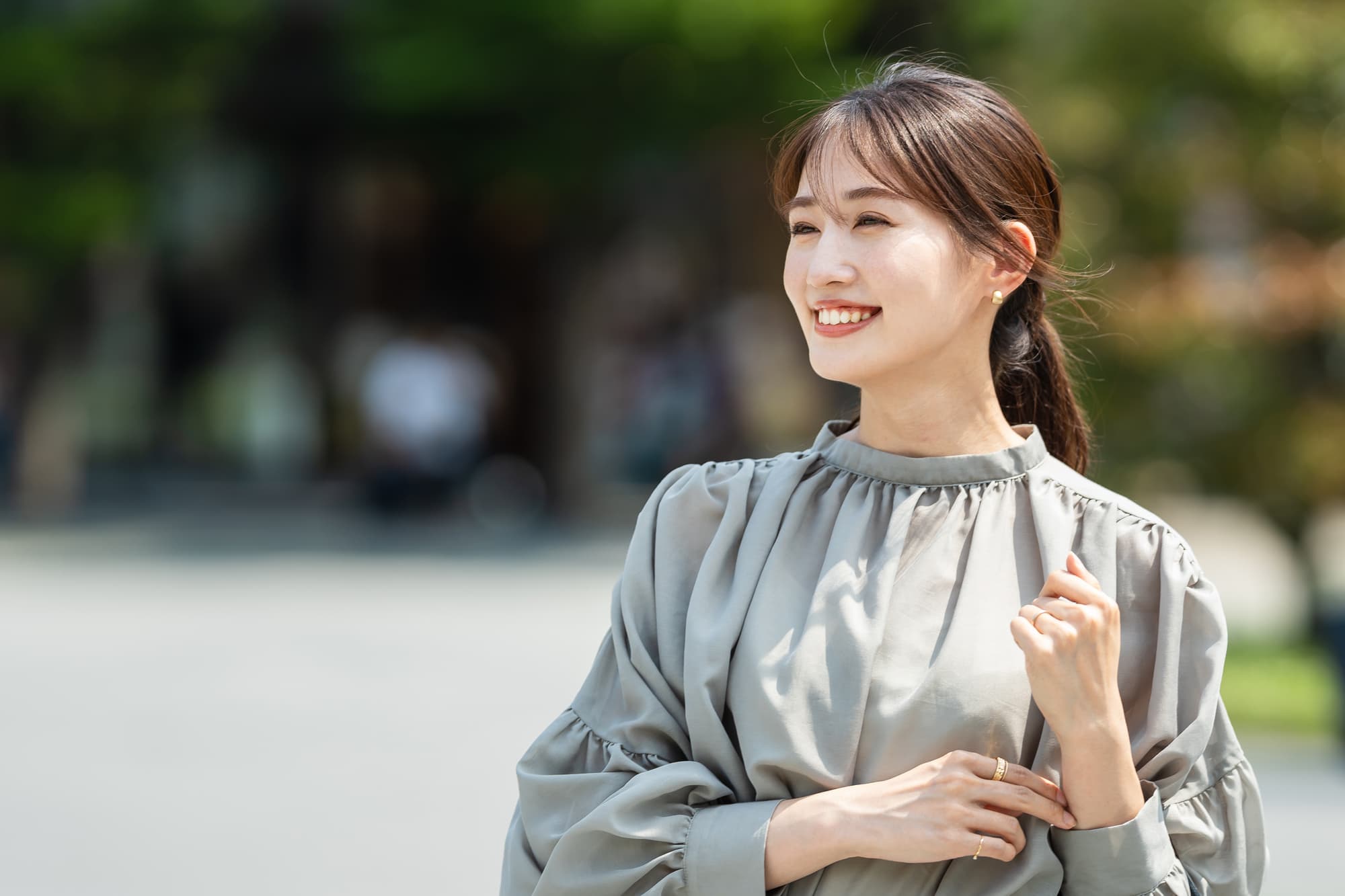 セラミックの歯にした女性が笑顔で散歩をしているイメージ