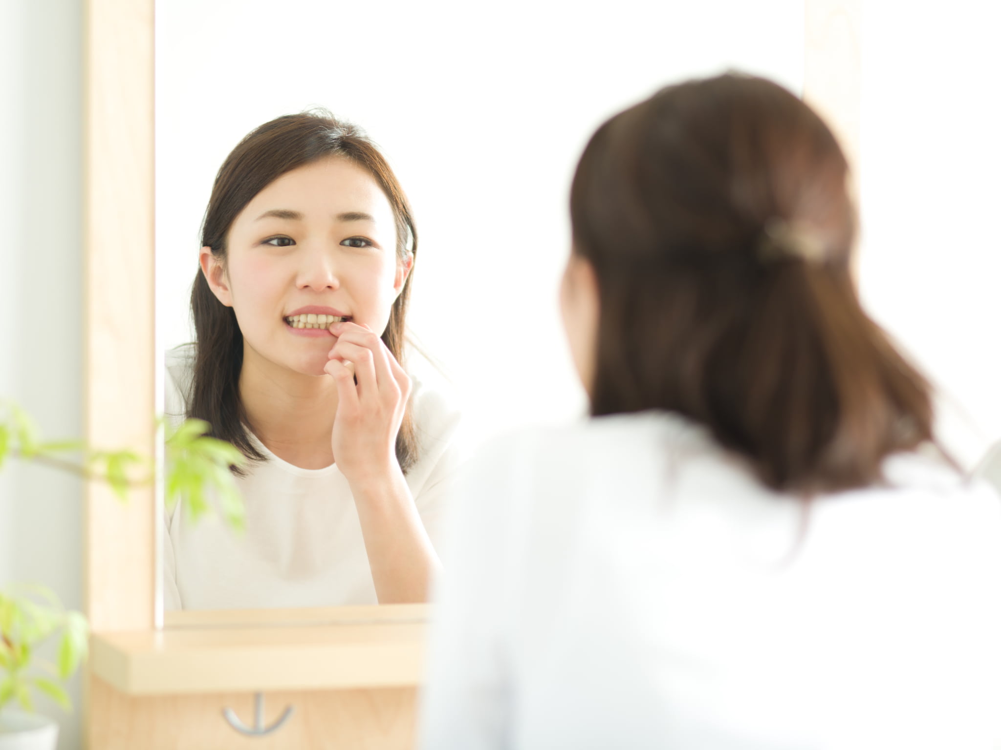 歯と歯の間に虫歯ができていないか鏡でチェックしている女性