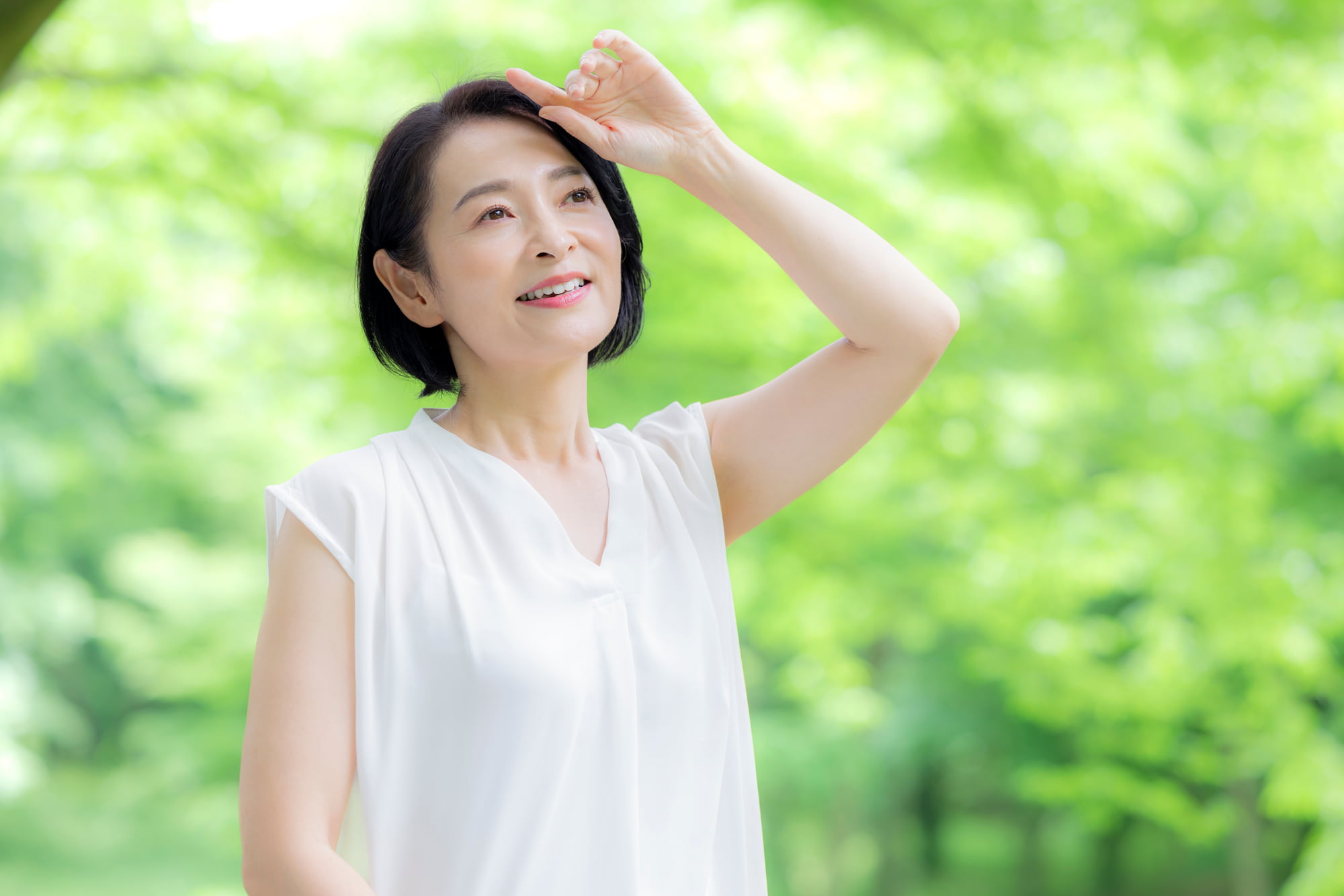 笑顔で緑の中を散歩するミドル女性
