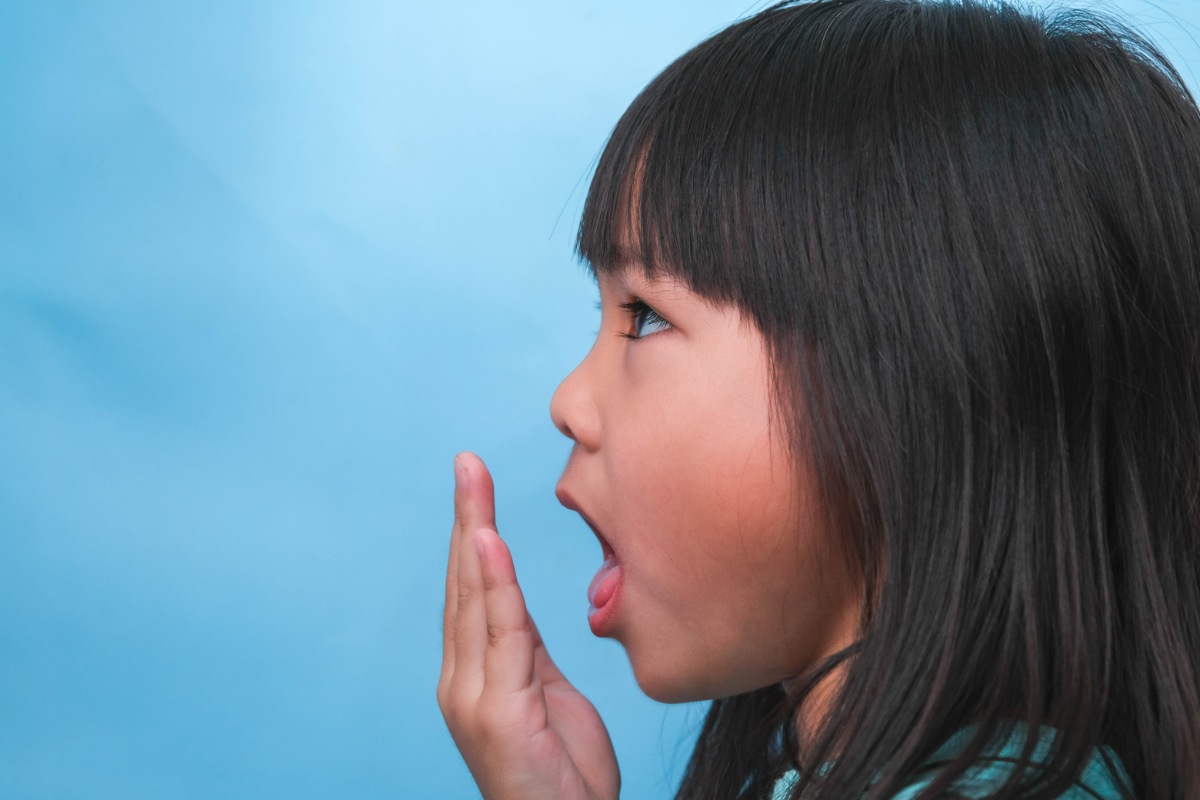 手に息を吹きかけて口臭を確認する子ども